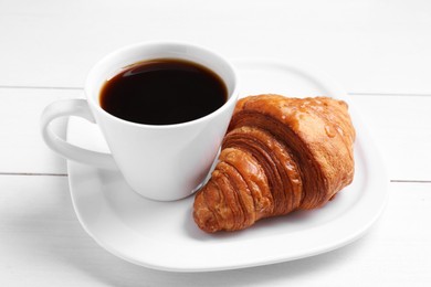 Photo of Tasty breakfast. Cup of coffee and croissant on white wooden table