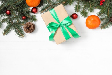 Photo of Flat lay composition with Christmas gift box and decor on white wooden table, space for text