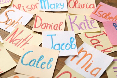 Photo of Paper notes with different baby names on wooden table
