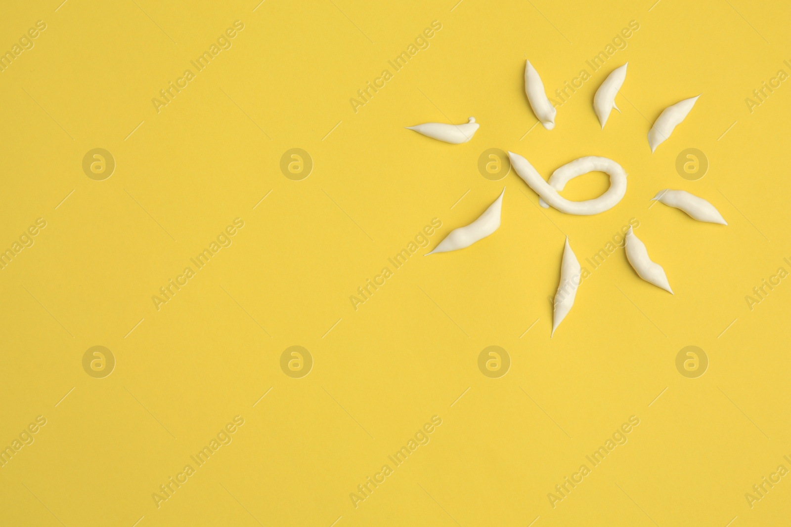 Photo of Drawing of sun with cream on yellow background, above view and space for text. Skin care and protection