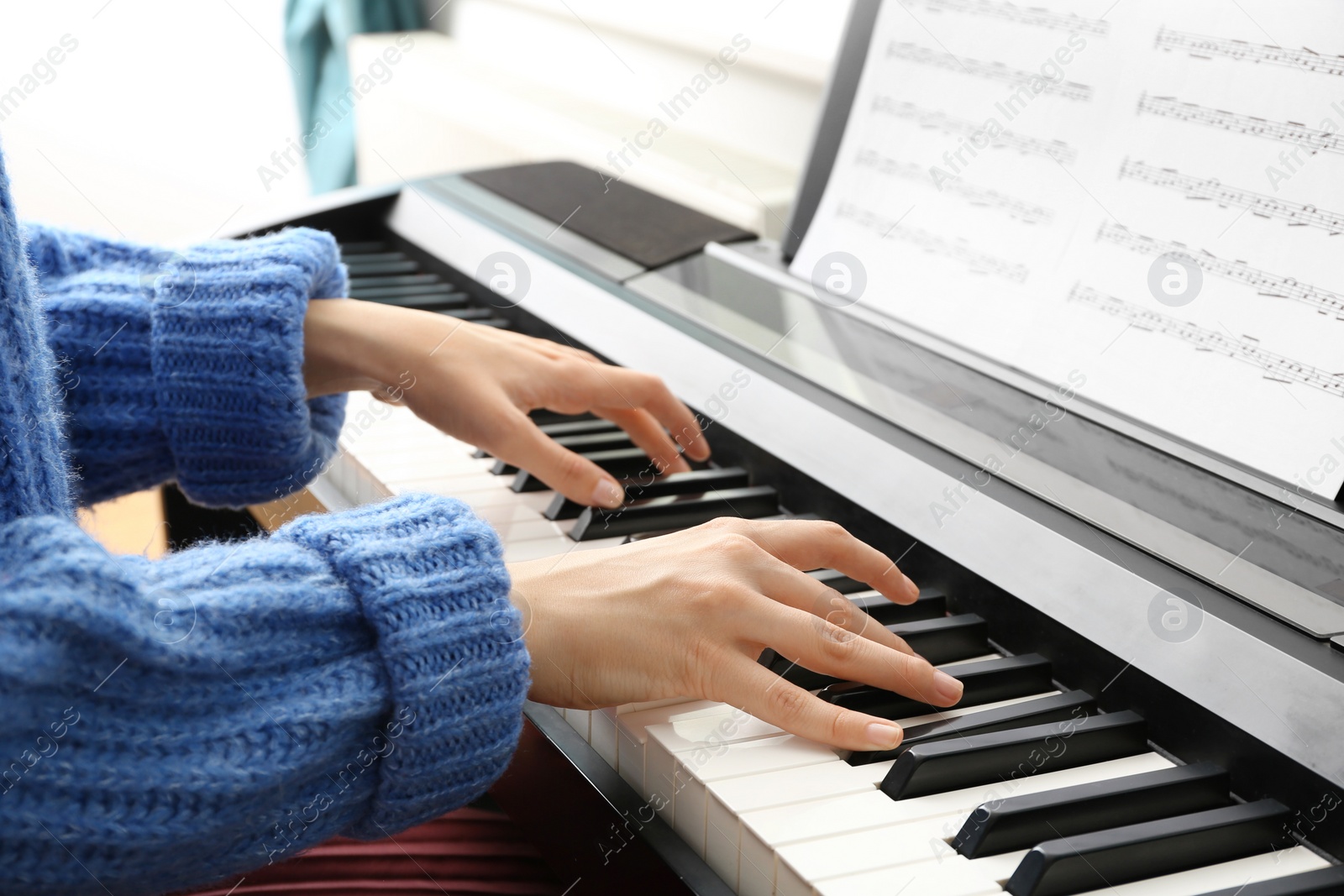 Photo of Young woman playing piano at home, closeup