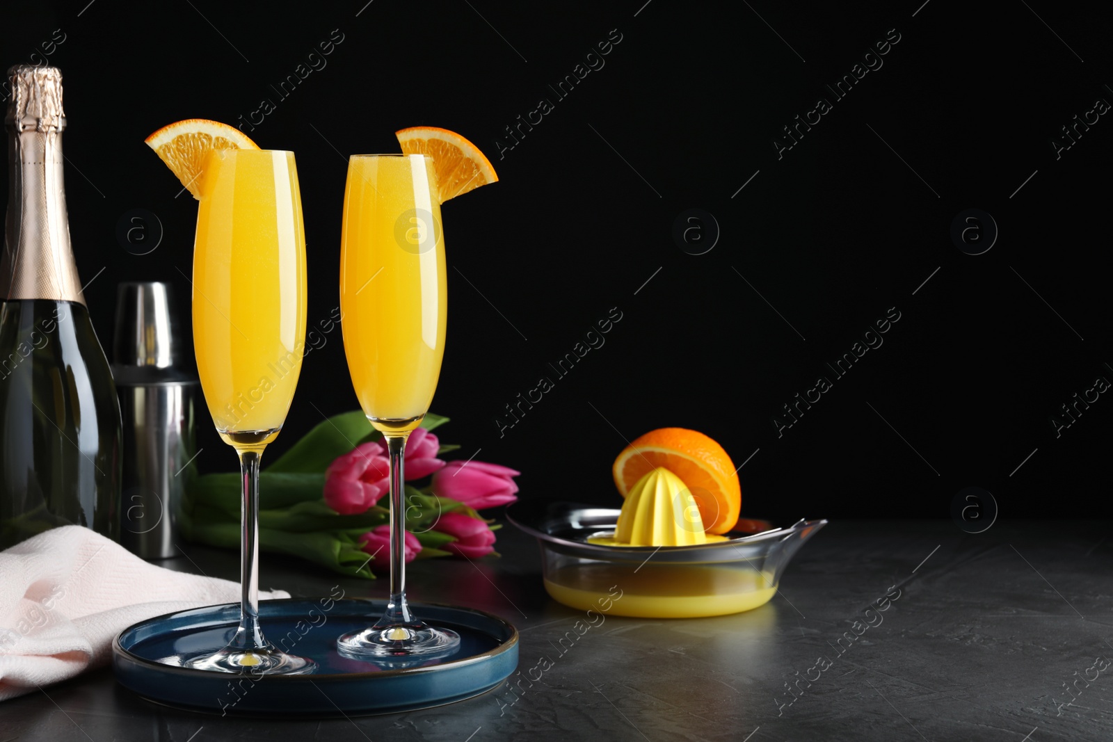 Photo of Glasses of Mimosa cocktail with garnish on grey table. Space for text