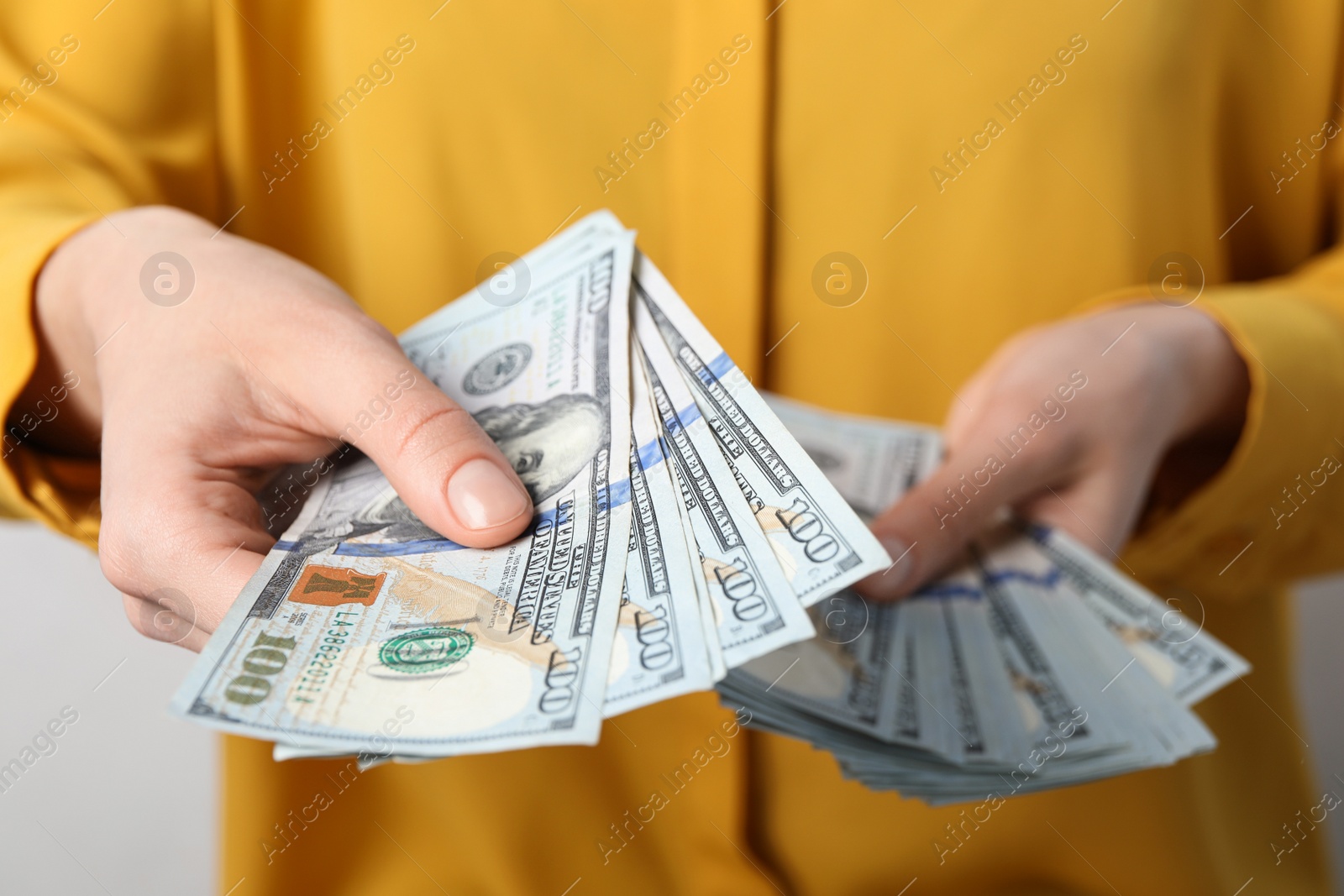 Photo of Woman counting dollar banknotes on light background, closeup