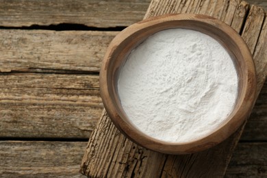 Photo of Baking powder in bowl on wooden table, top view. Space for text