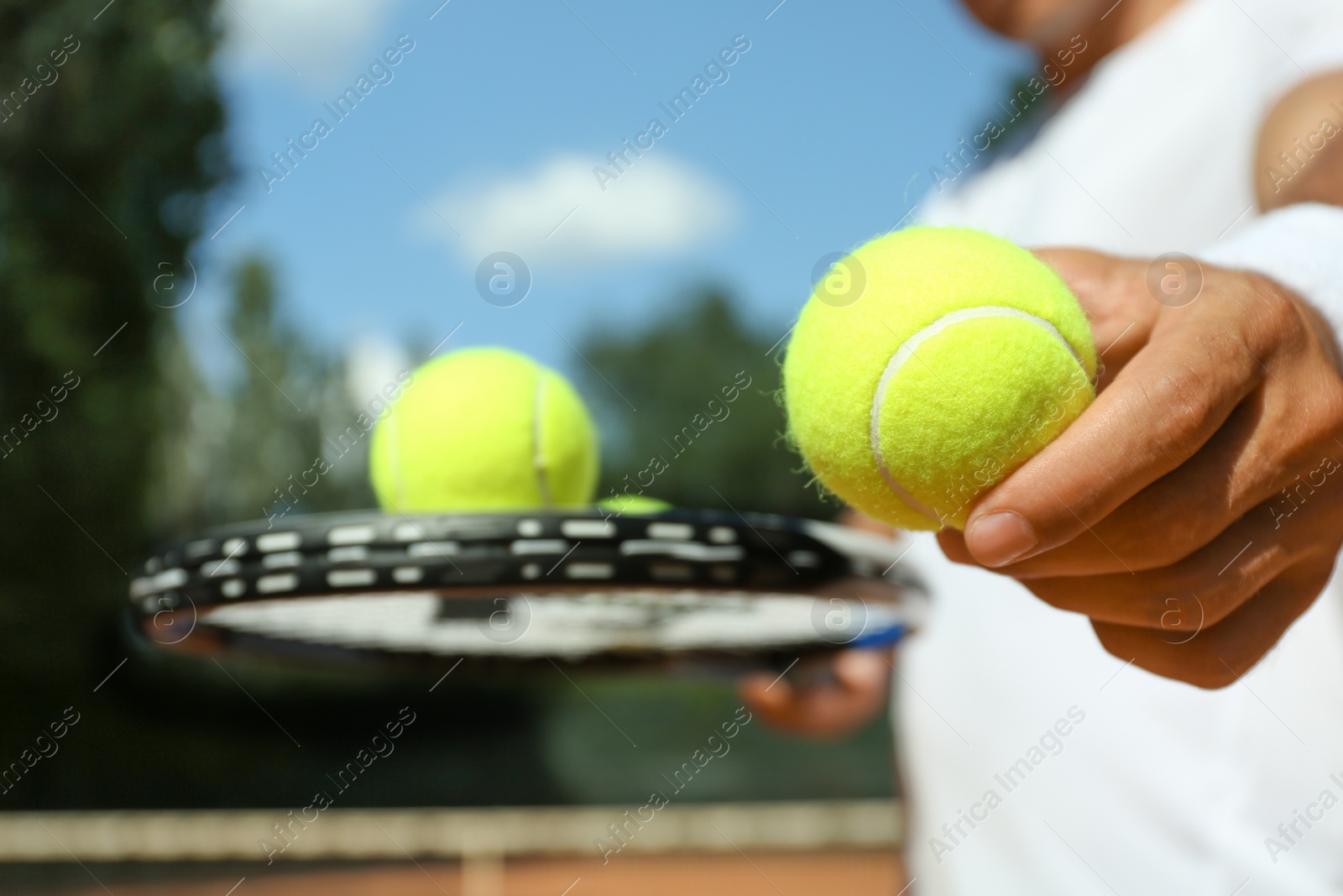 Photo of Sportsman with racket and tennis balls at court, closeup