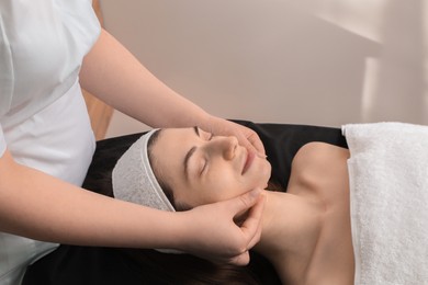 Photo of Cosmetologist making face massage to client in clinic, closeup