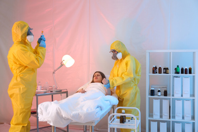 Photo of Paramedics wearing protective suits examining patient with virus in quarantine ward