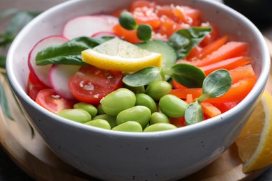 Photo of Poke bowl with salmon, edamame beans and vegetables on wooden table, closeup