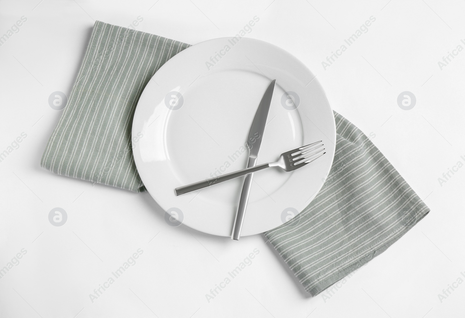 Photo of Ceramic plate, fork and knife on white background, top view