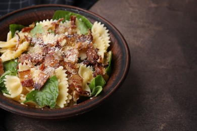 Tasty pasta with bacon and basil on brown table, space for text