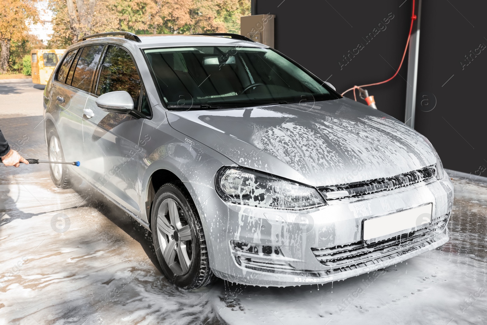 Photo of Man washing auto with high pressure water jet at outdoor car wash, closeup