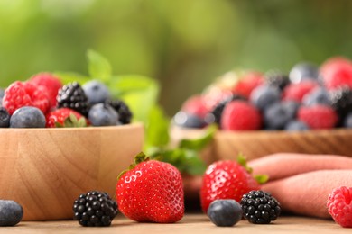 Photo of Bowls with different fresh ripe berries and mint on table outdoors, closeup