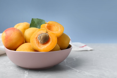 Delicious fresh ripe apricots in bowl on grey table. Space for text