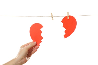 Photo of Woman with halves of paper heart on white background. Relationship problems