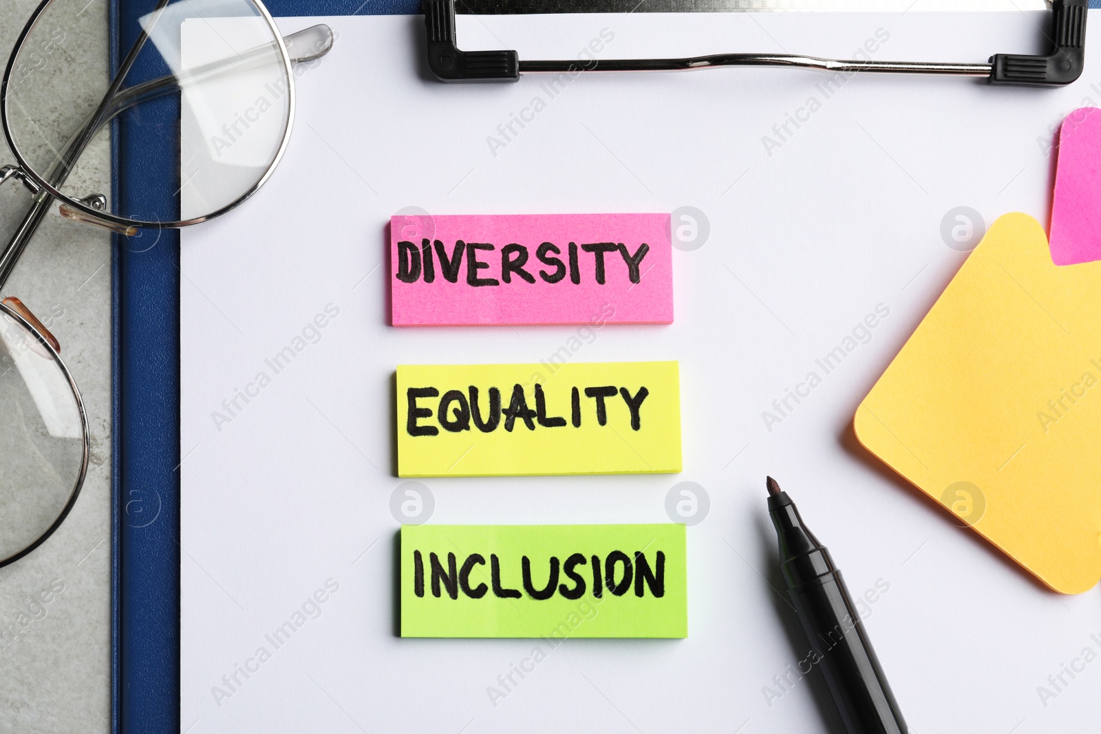 Photo of Sticky notes with words Diversity, Equality, Inclusion, marker and glasses on grey table, top view