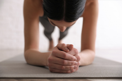 Photo of Young woman practicing forearm plank asana in yoga studio, closeup. Phalankasana pose variation