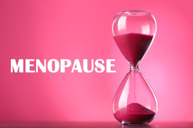Menopause word and hourglass on pink background
