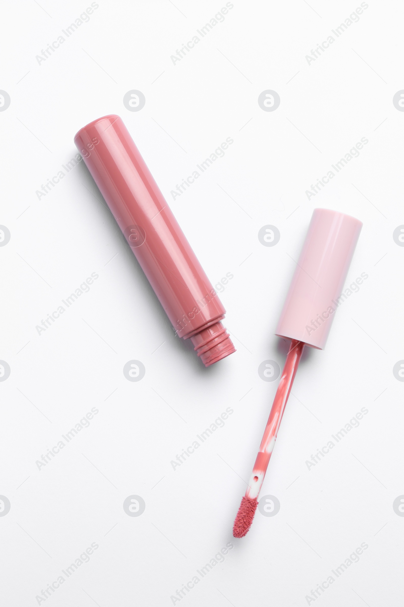 Photo of Pink lip gloss and applicator on white background, top view