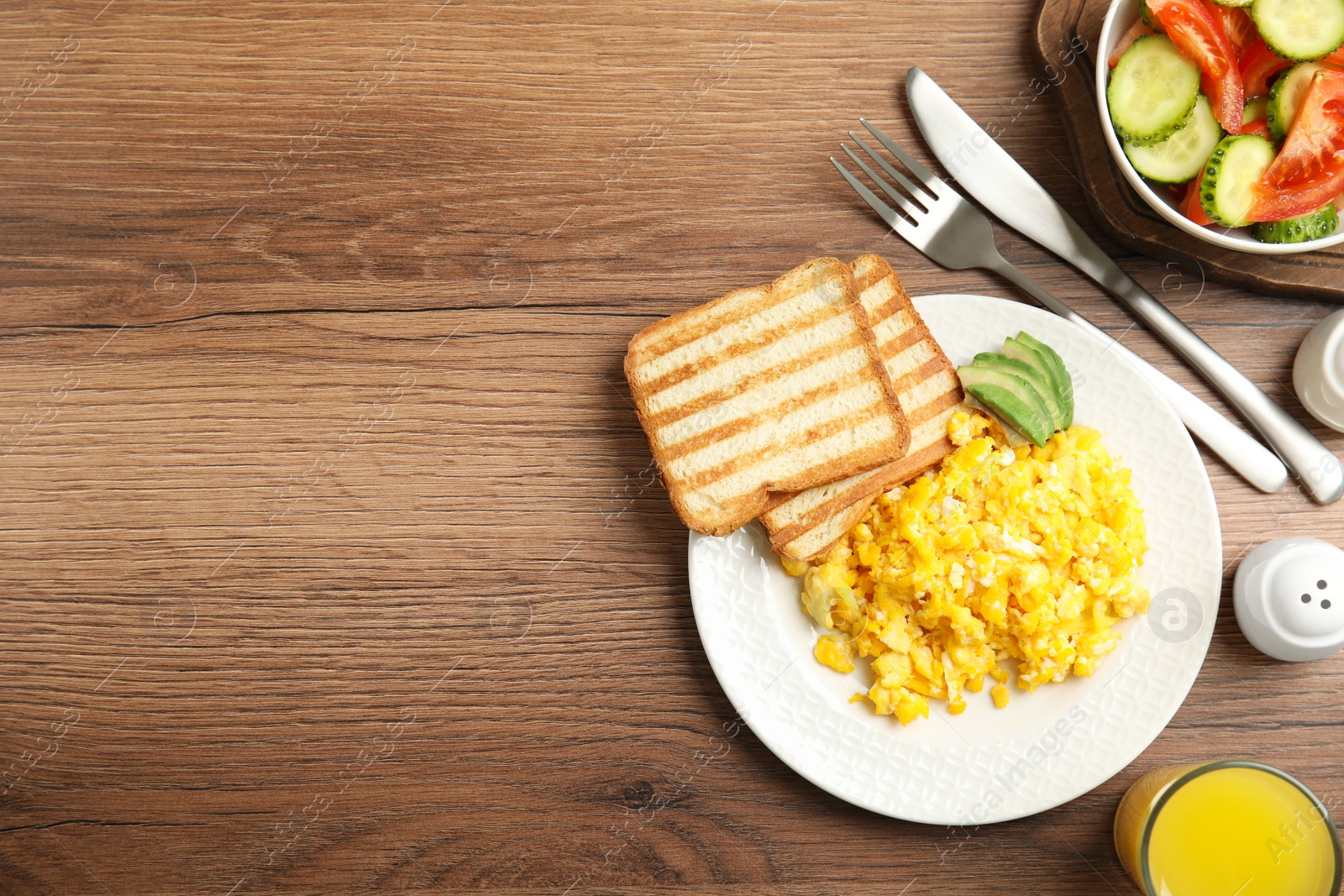 Photo of Delicious breakfast with scrambled eggs served on wooden table, flat lay. Space for text