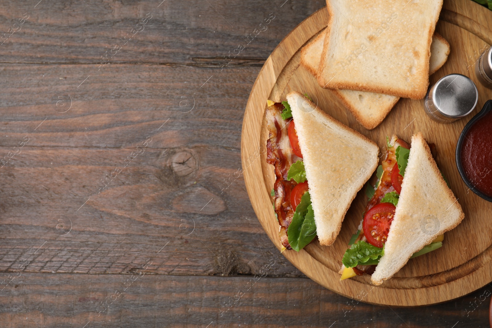 Photo of Delicious sandwiches with fried bacon on wooden table, top view. Space for text