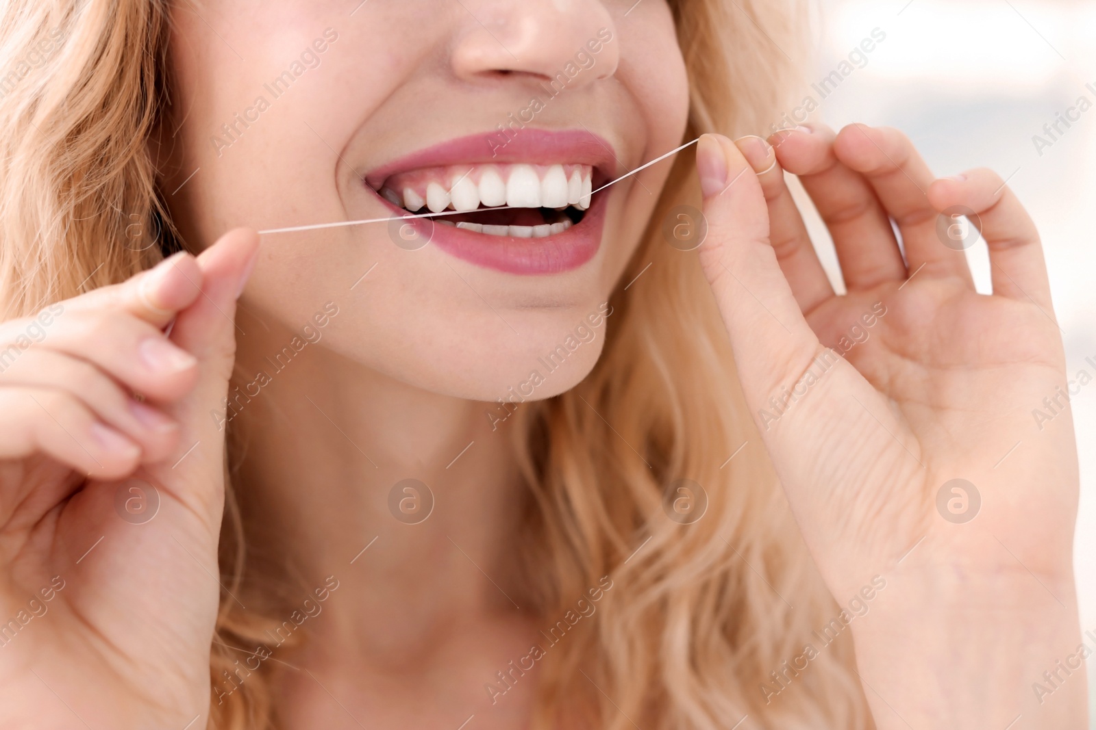 Photo of Young woman flossing her teeth, closeup