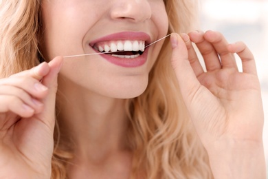 Photo of Young woman flossing her teeth, closeup