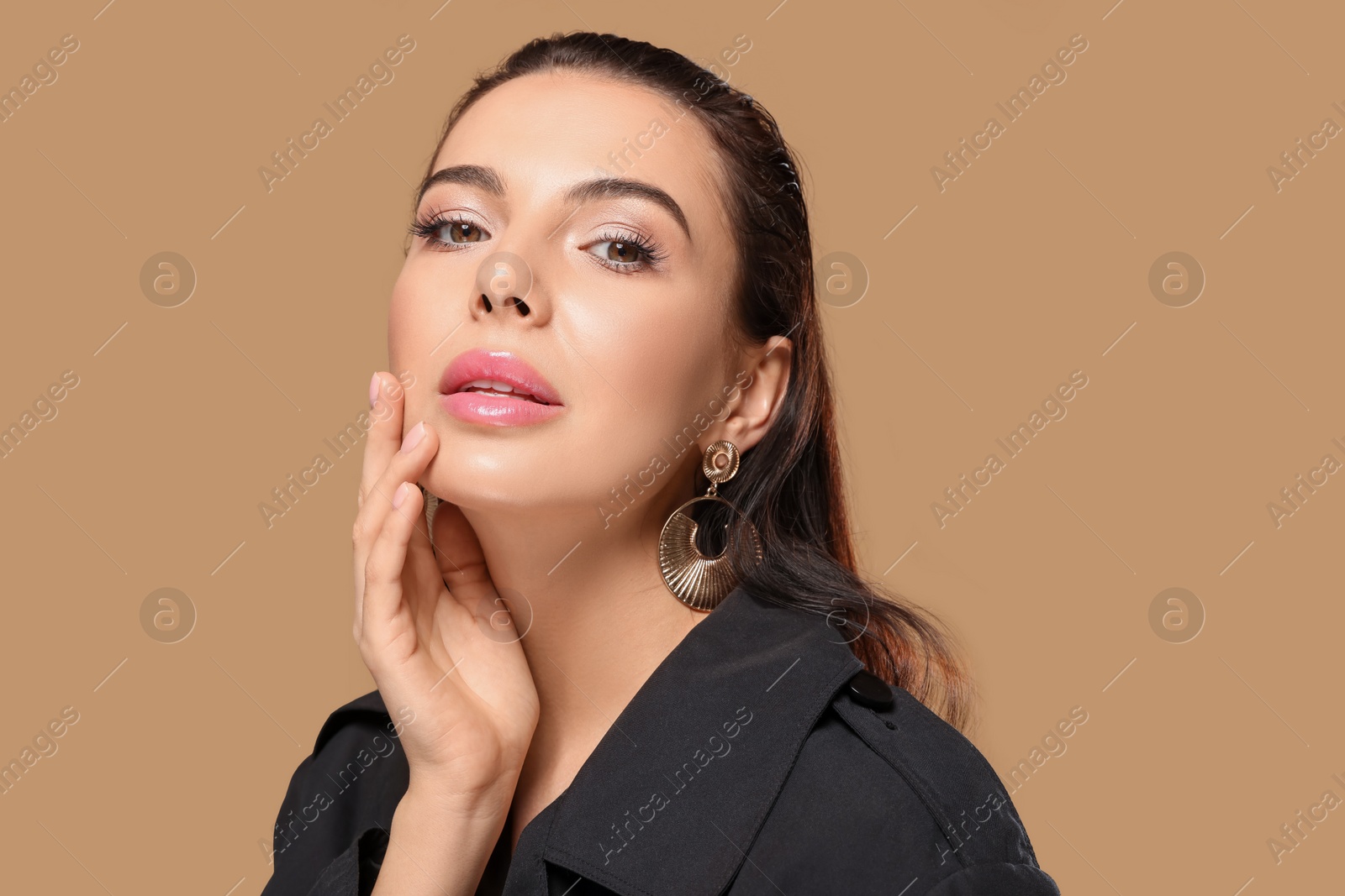 Photo of Portrait of young woman with beautiful makeup on light brown background