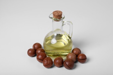 Photo of Delicious organic Macadamia nuts and natural oil on white background