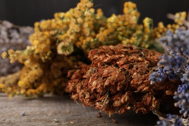 Photo of Many different dry herbs on wooden table, closeup