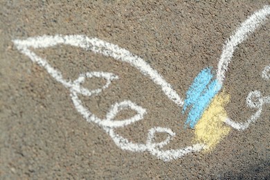 Photo of Angel drawn with colorful chalks on asphalt outdoors, closeup