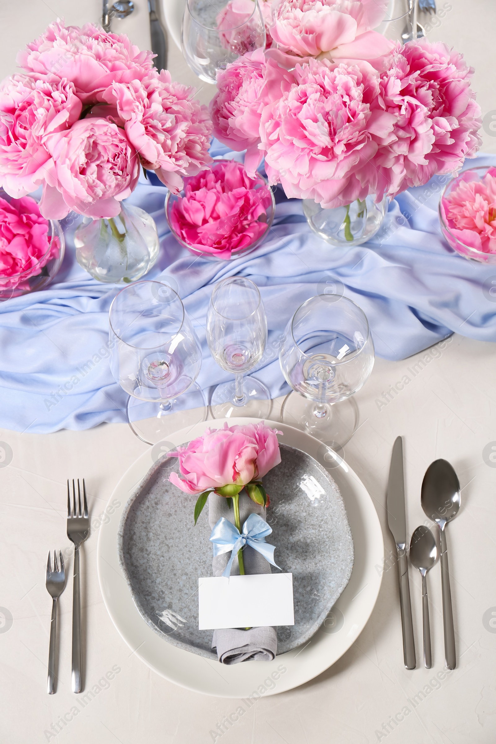 Photo of Stylish table setting with beautiful peonies, napkin and blank card, above view