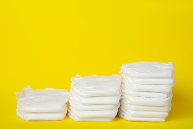 Photo of Stacks of diapers on yellow background. Space for text