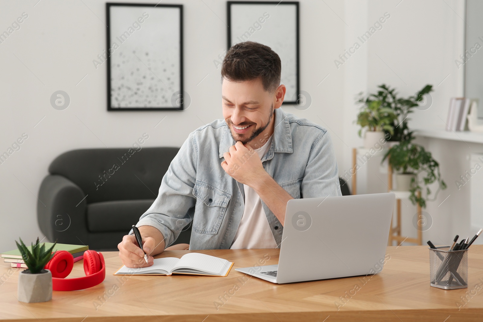 Photo of Online translation course. Man writing near laptop at home