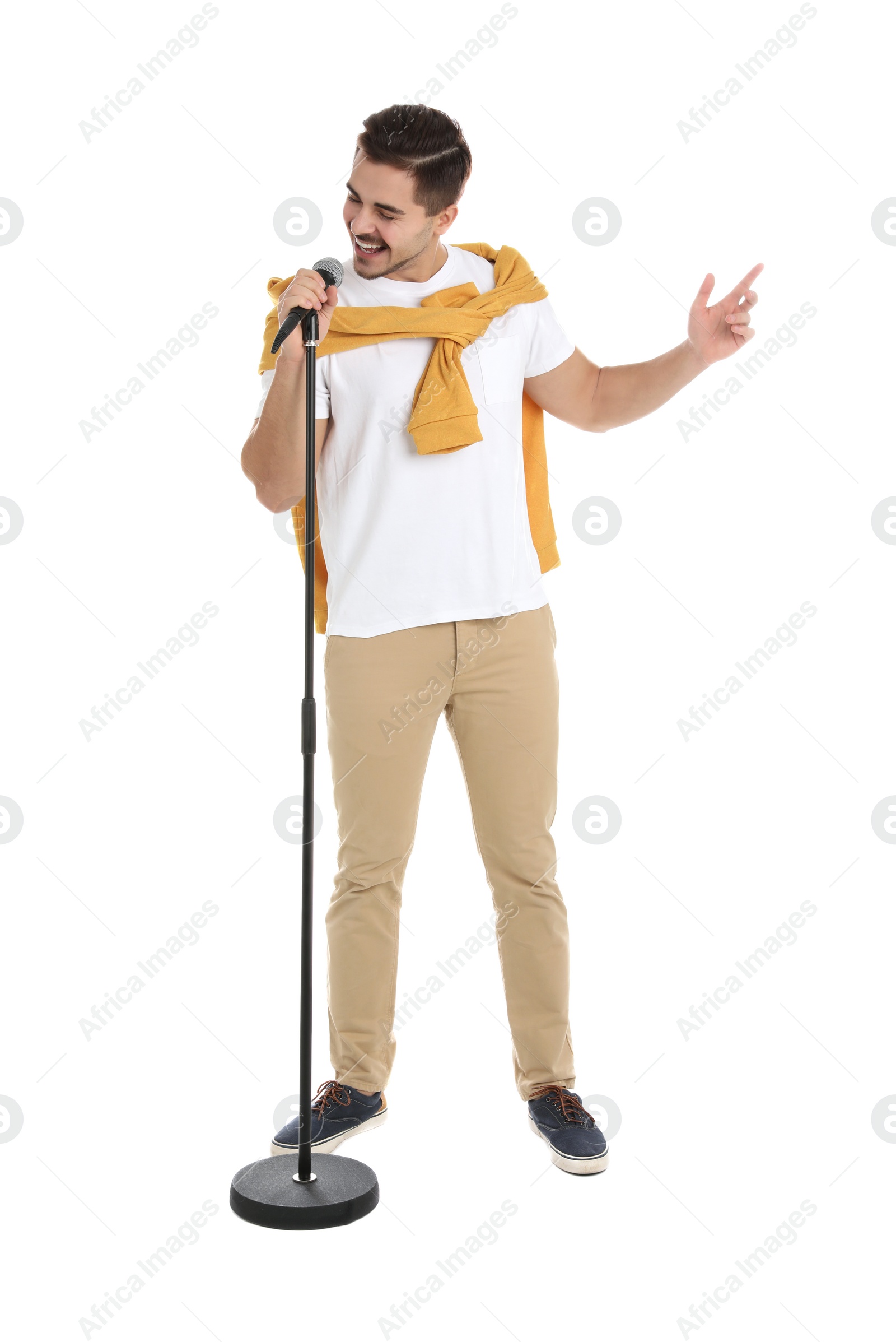 Photo of Young handsome man in casual clothes singing with microphone on white background