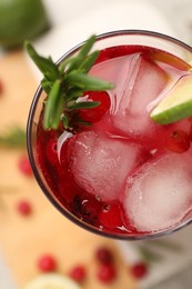 Photo of Tasty cranberry cocktail with rosemary and lime in glass on table, top view
