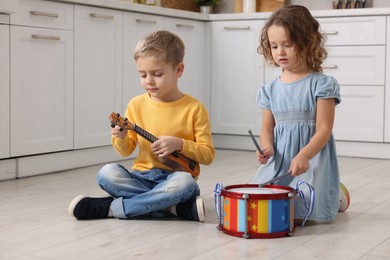 Photo of Little children playing toy musical instruments in kitchen