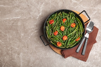 Photo of Tasty green beans with cherry tomatoes in serving pan on table, top view