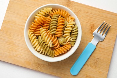 Photo of Bowl with tasty fusilli pasta and fork on white table, top view
