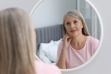 Photo of Beautiful senior woman near mirror in room