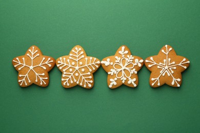 Photo of Tasty Christmas cookies with icing on green background, flat lay