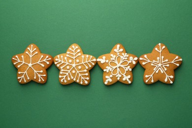 Tasty Christmas cookies with icing on green background, flat lay