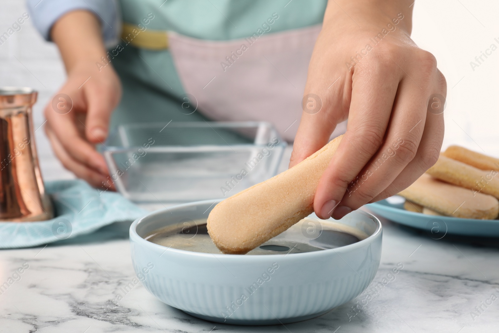 Photo of Woman making tiramisu cake at white marble table, closeup