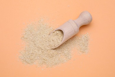 Photo of Scoop with beer yeast flakes on pale orange background, top view