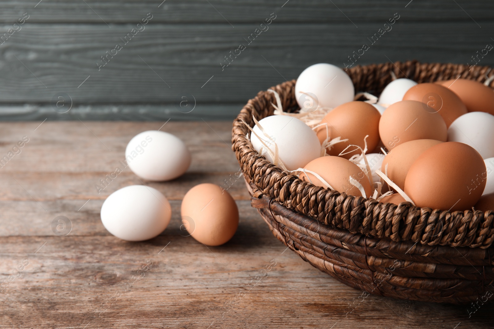 Photo of Basket with raw chicken eggs on wooden table