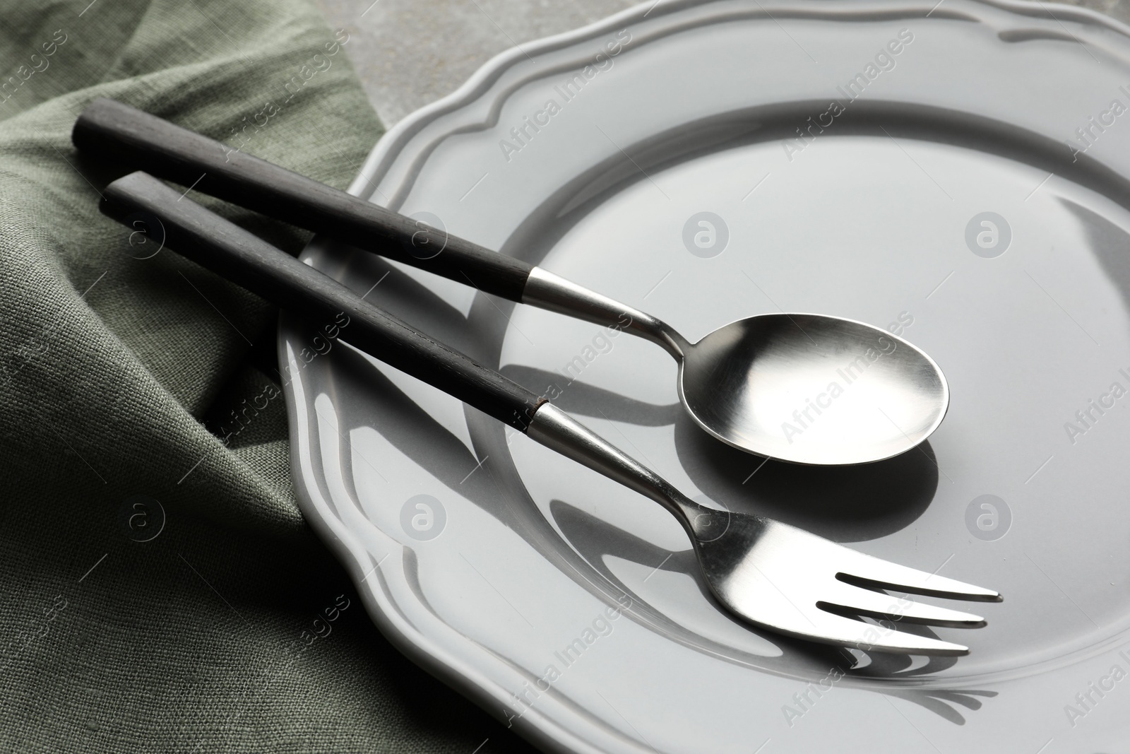 Photo of Stylish setting with cutlery, napkin and plate on table, closeup