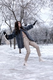 Photo of Young woman falling on slippery icy pavement in park