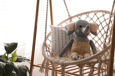 Photo of Wooden swing with toy elephant indoors. Interior design