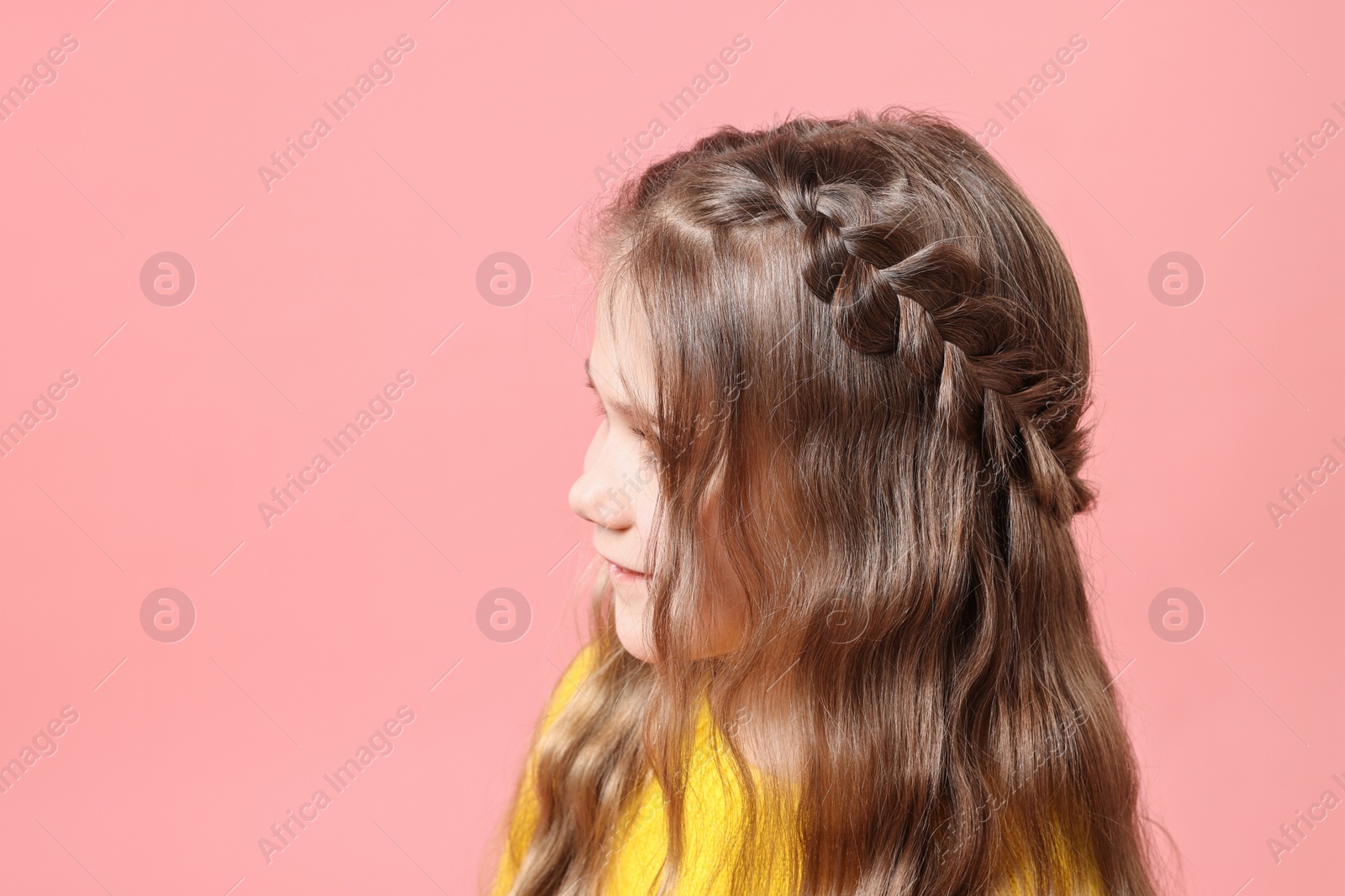 Photo of Cute little girl with braided hair on pink background