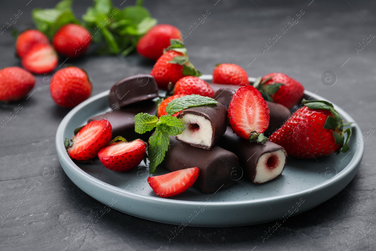 Photo of Delicious glazed curd snacks with fresh strawberries and mint on black table