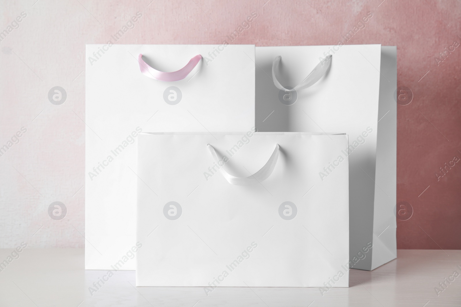 Photo of Paper shopping bags on table against color background. Mock up for design